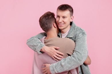 Photo of Two happy friends hugging on pink background