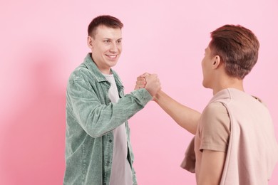 Photo of Friends welcoming each other on pink background