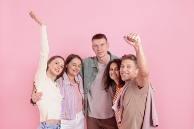 Photo of Group of friends hugging each other on pink background