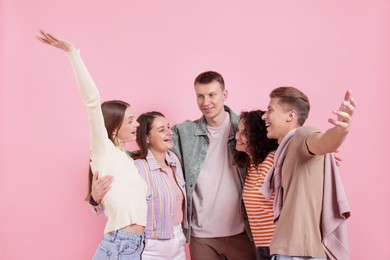 Photo of Group of friends hugging each other on pink background