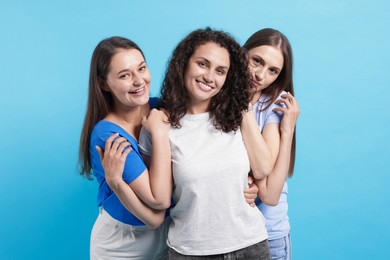 Photo of Three friends hugging on light blue background