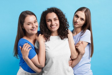 Photo of Three friends hugging on light blue background