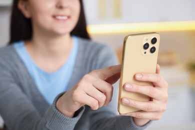 Photo of Woman using modern smartphone at home, selective focus