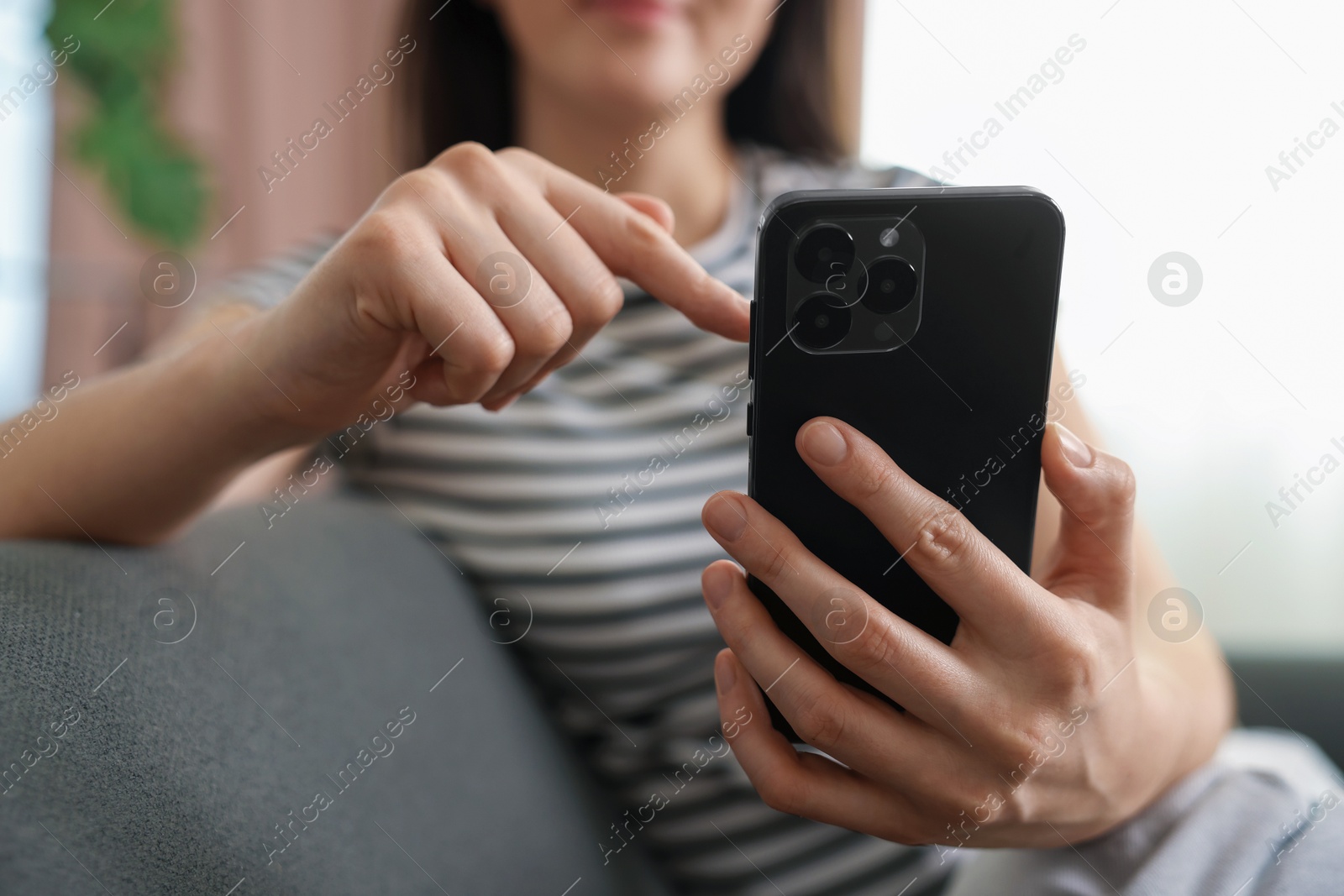 Photo of Woman using modern smartphone on sofa at home, closeup