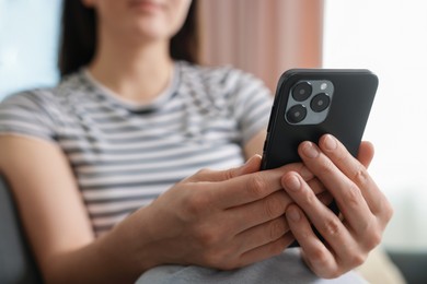 Photo of Woman using modern smartphone at home, closeup