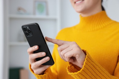 Photo of Woman using modern smartphone at home, closeup