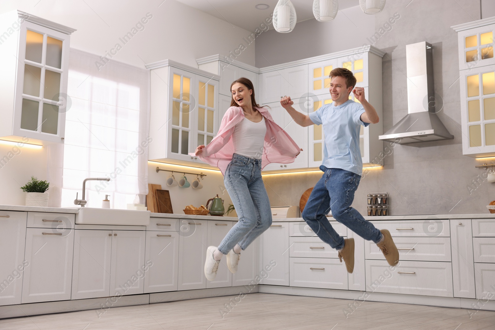 Photo of Happy couple jumping while dancing in kitchen