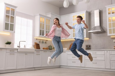 Photo of Happy couple jumping while dancing in kitchen