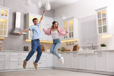 Photo of Happy couple jumping while dancing in kitchen