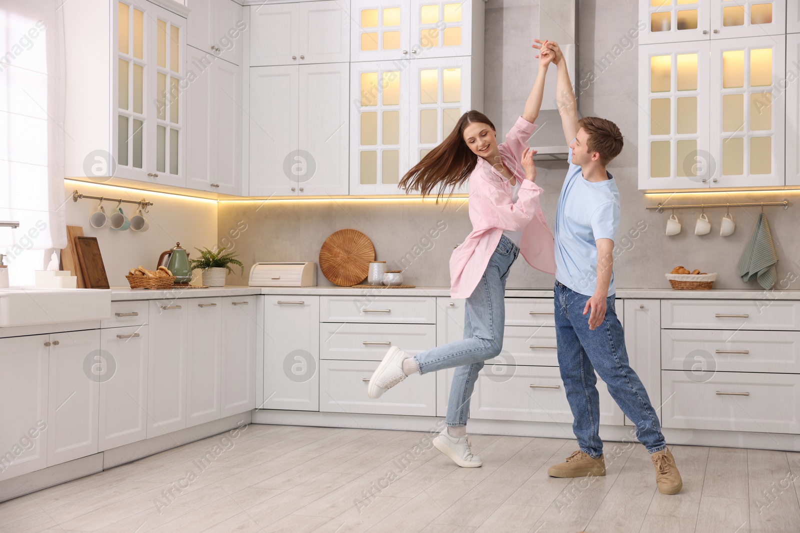 Photo of Happy young couple dancing together in kitchen