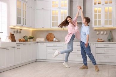 Photo of Happy young couple dancing together in kitchen