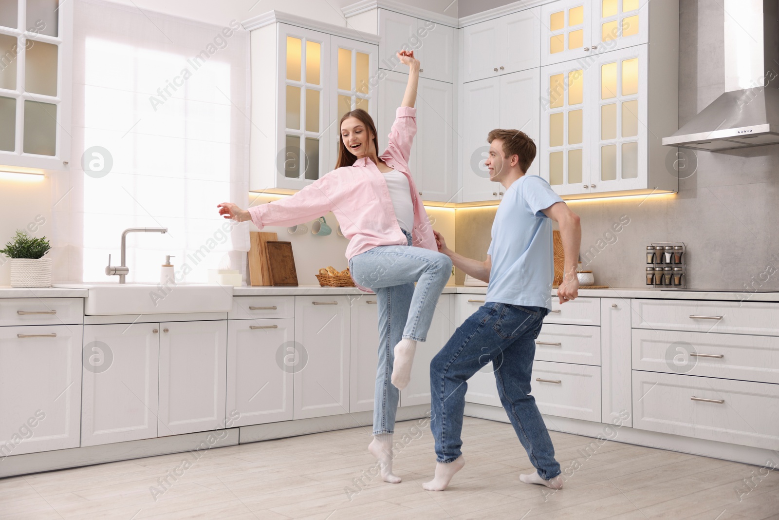 Photo of Happy young couple dancing together in kitchen