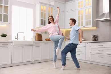 Photo of Happy young couple dancing together in kitchen