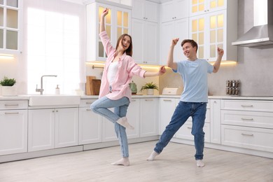 Photo of Happy young couple dancing together in kitchen
