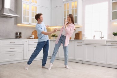 Photo of Happy young couple dancing together in kitchen