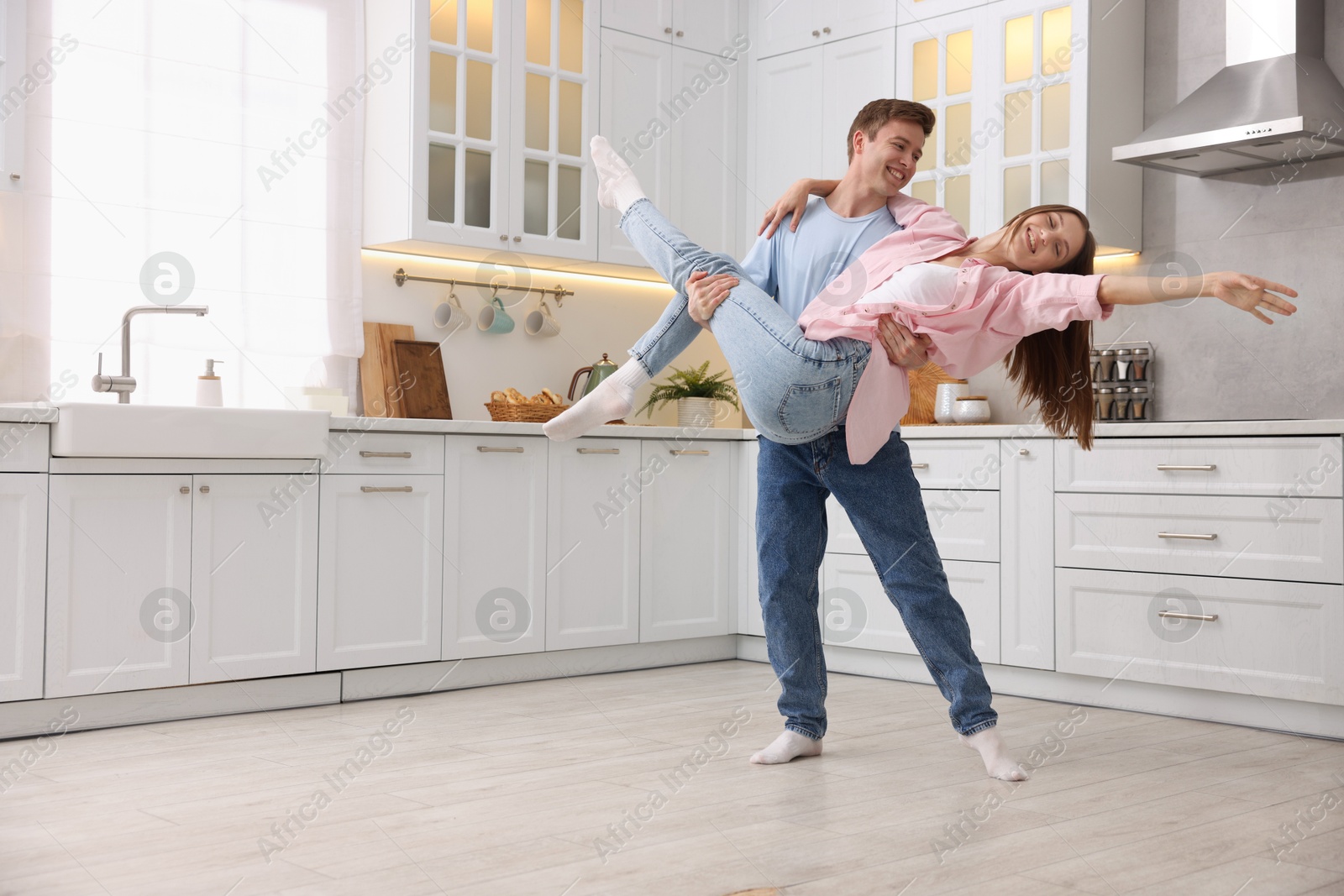 Photo of Happy young couple dancing together in kitchen