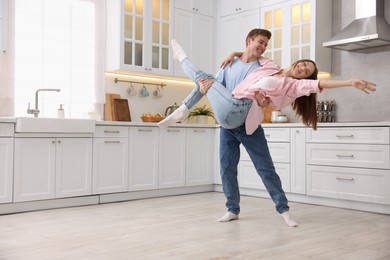 Photo of Happy young couple dancing together in kitchen