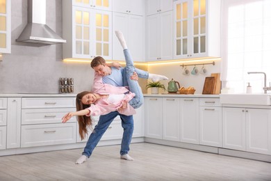 Photo of Happy young couple dancing together in kitchen