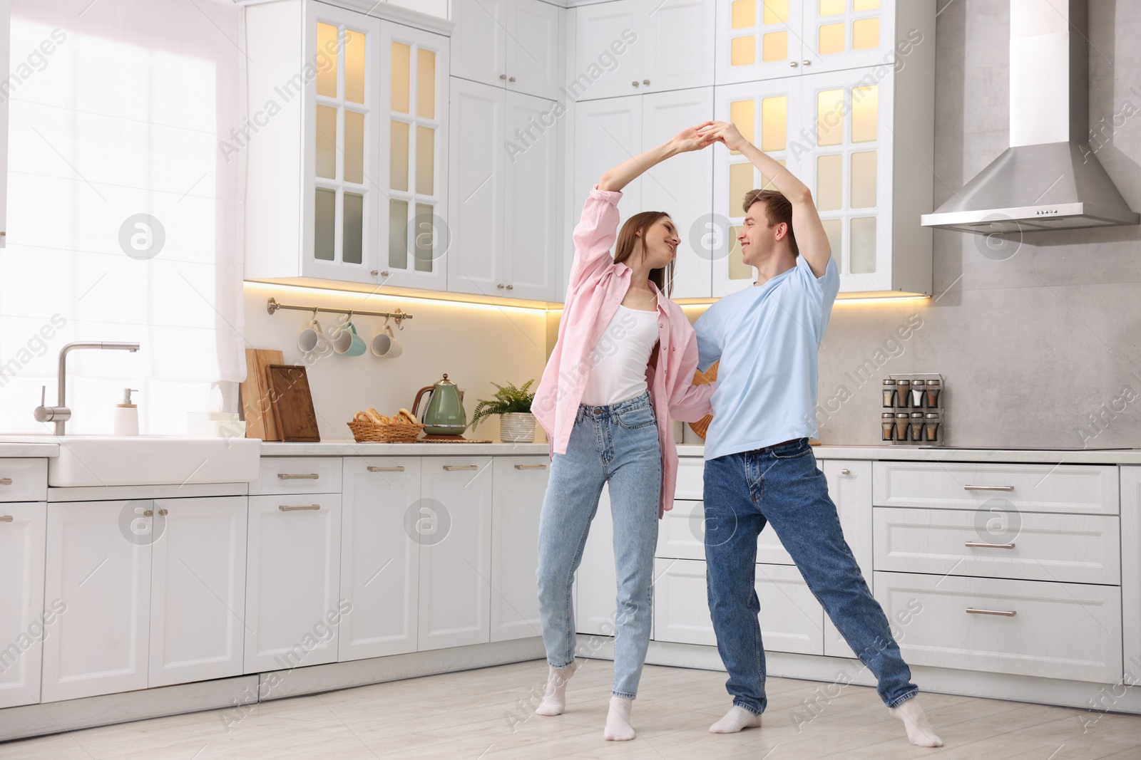 Photo of Happy young couple dancing together in kitchen