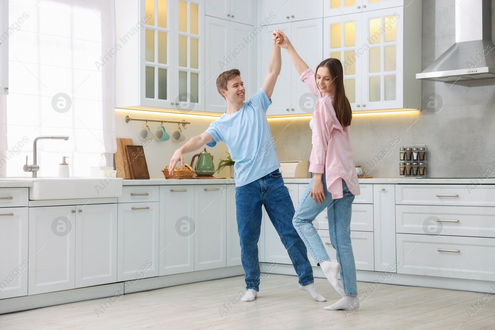 Photo of Happy young couple dancing together in kitchen