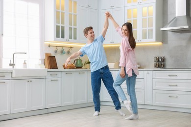 Photo of Happy young couple dancing together in kitchen