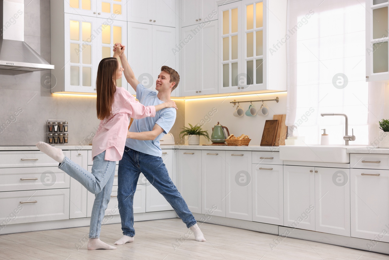 Photo of Happy young couple dancing together in kitchen