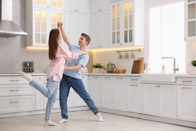 Photo of Happy young couple dancing together in kitchen