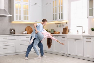 Photo of Carefree young couple dancing together in kitchen