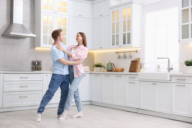 Photo of Happy young couple dancing together in kitchen