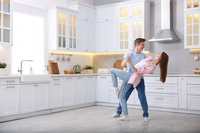 Photo of Happy young couple dancing together in kitchen