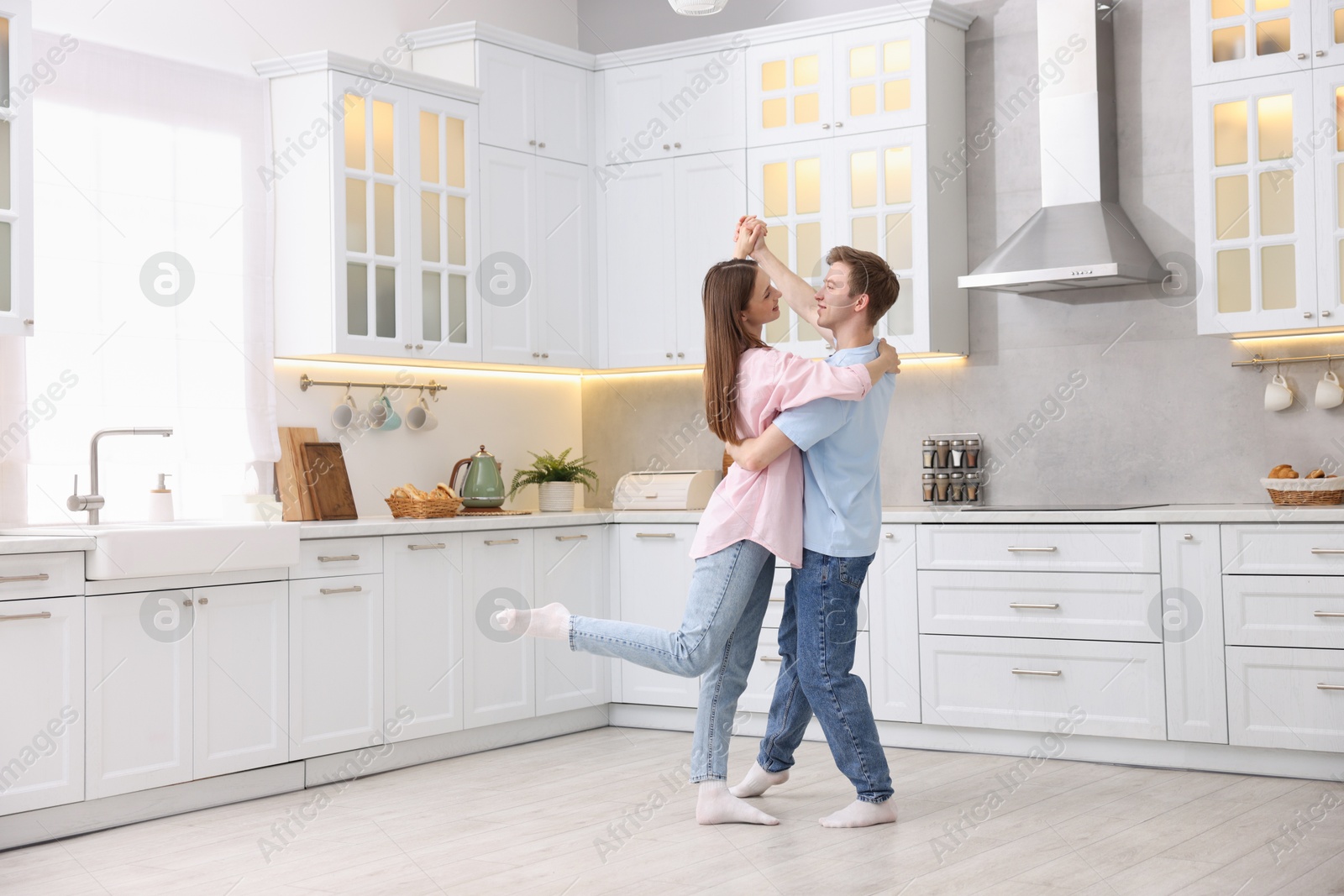 Photo of Happy young couple dancing together in kitchen