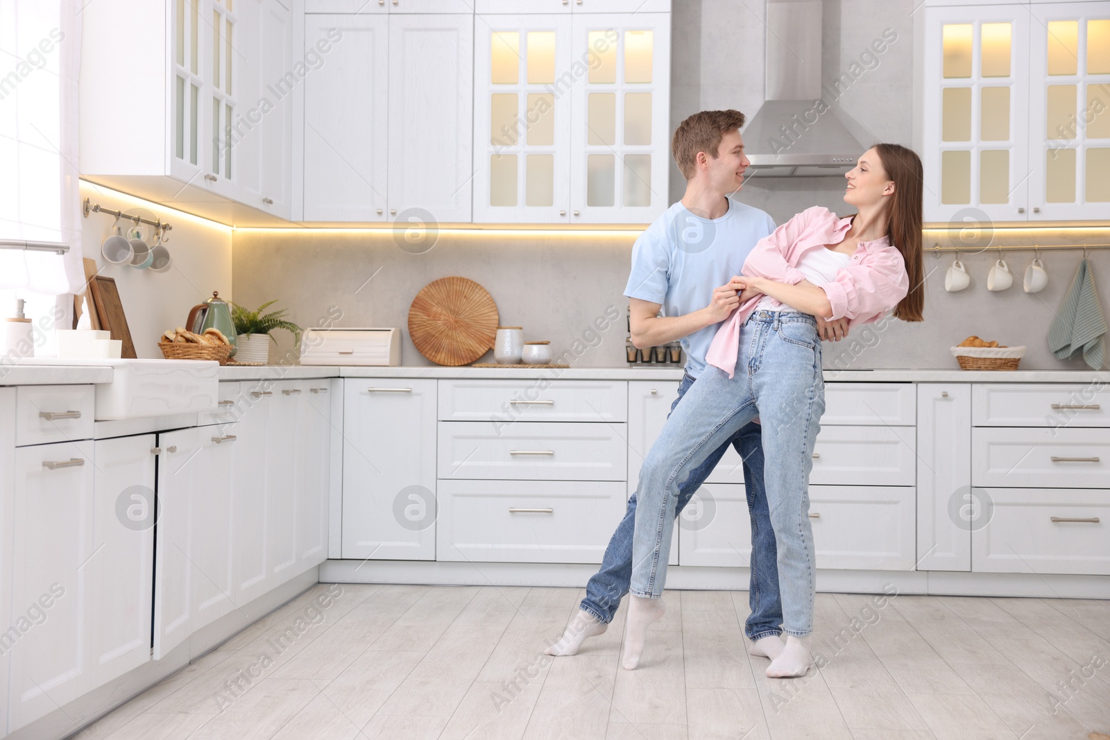 Photo of Happy young couple dancing together in kitchen