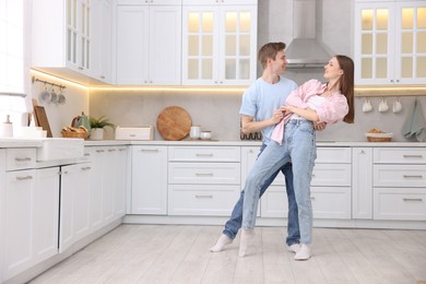 Photo of Happy young couple dancing together in kitchen