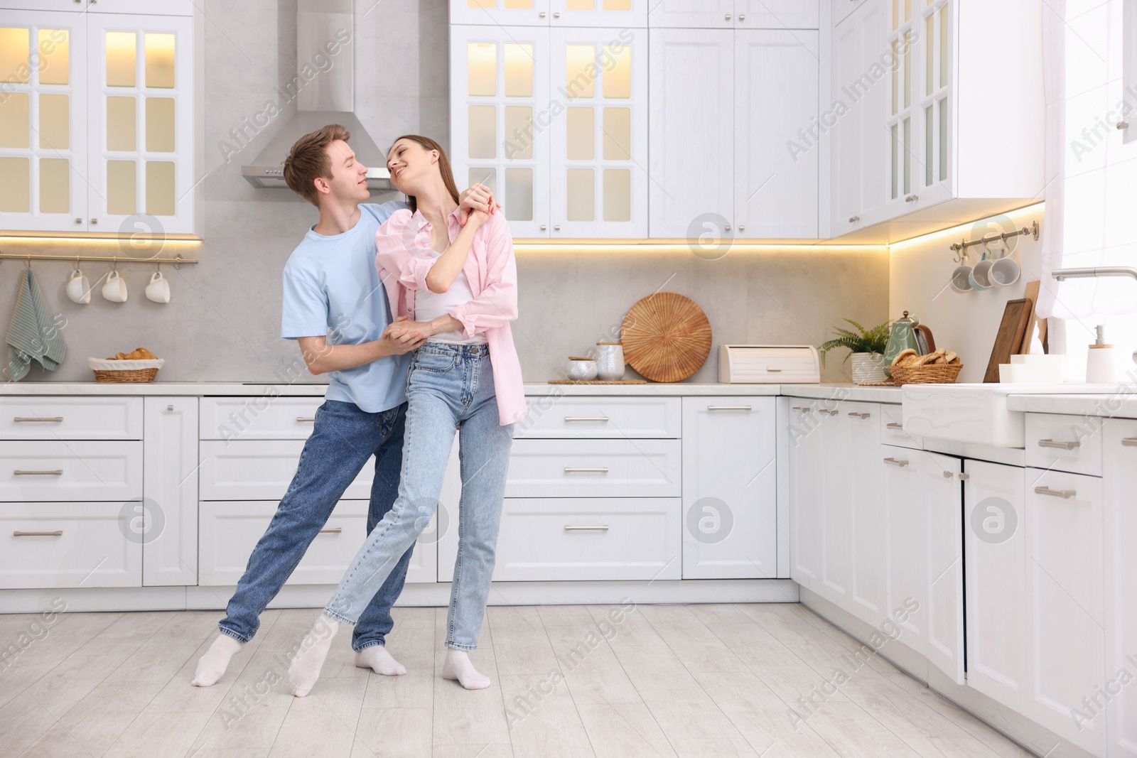 Photo of Happy young couple dancing together in kitchen