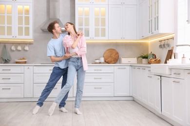 Photo of Happy young couple dancing together in kitchen