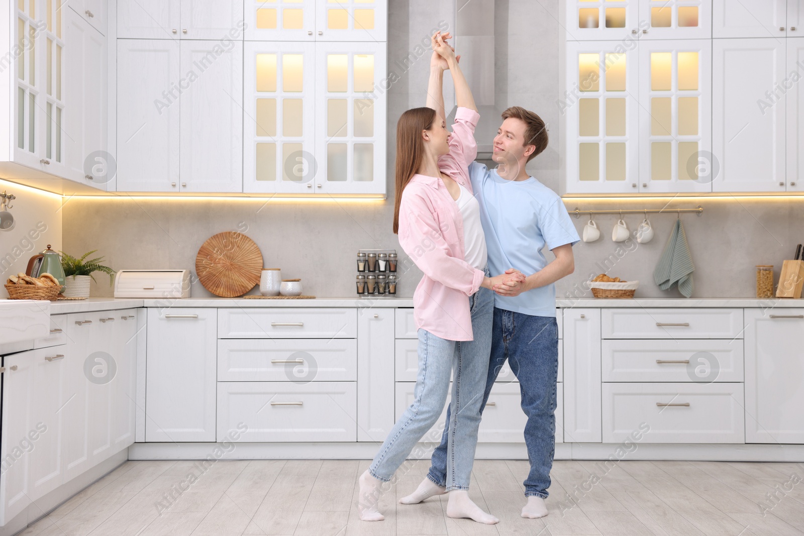 Photo of Happy young couple dancing together in kitchen