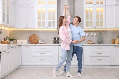 Photo of Happy young couple dancing together in kitchen