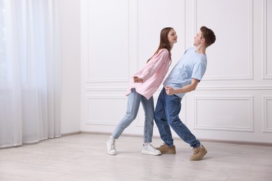 Photo of Happy couple dancing together near white wall at home