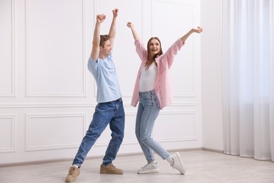Photo of Happy couple dancing together near white wall at home