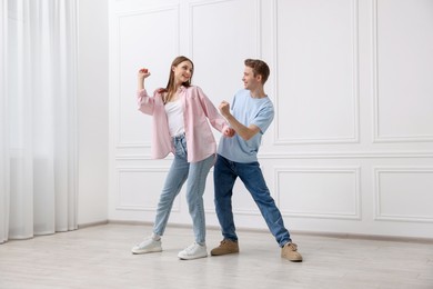 Photo of Happy couple dancing together near white wall at home