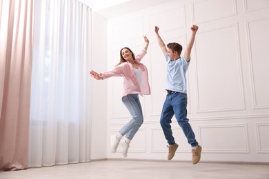 Photo of Happy couple dancing together near white wall at home, low angle view