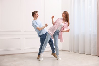 Photo of Happy couple dancing together near white wall at home