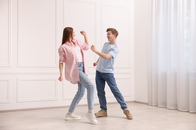 Photo of Happy couple dancing together near white wall at home