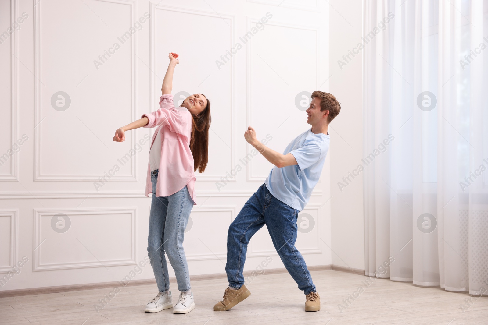 Happy couple dancing together near white wall at home Photo of Happy couple dancing together near white wall at home