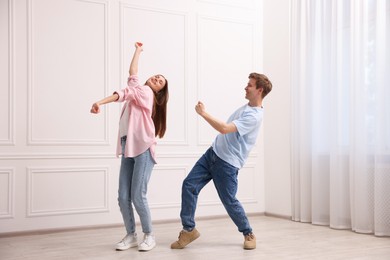 Photo of Happy couple dancing together near white wall at home