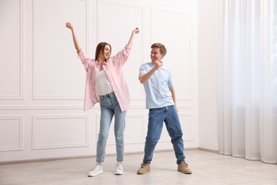Photo of Happy couple dancing together near white wall at home