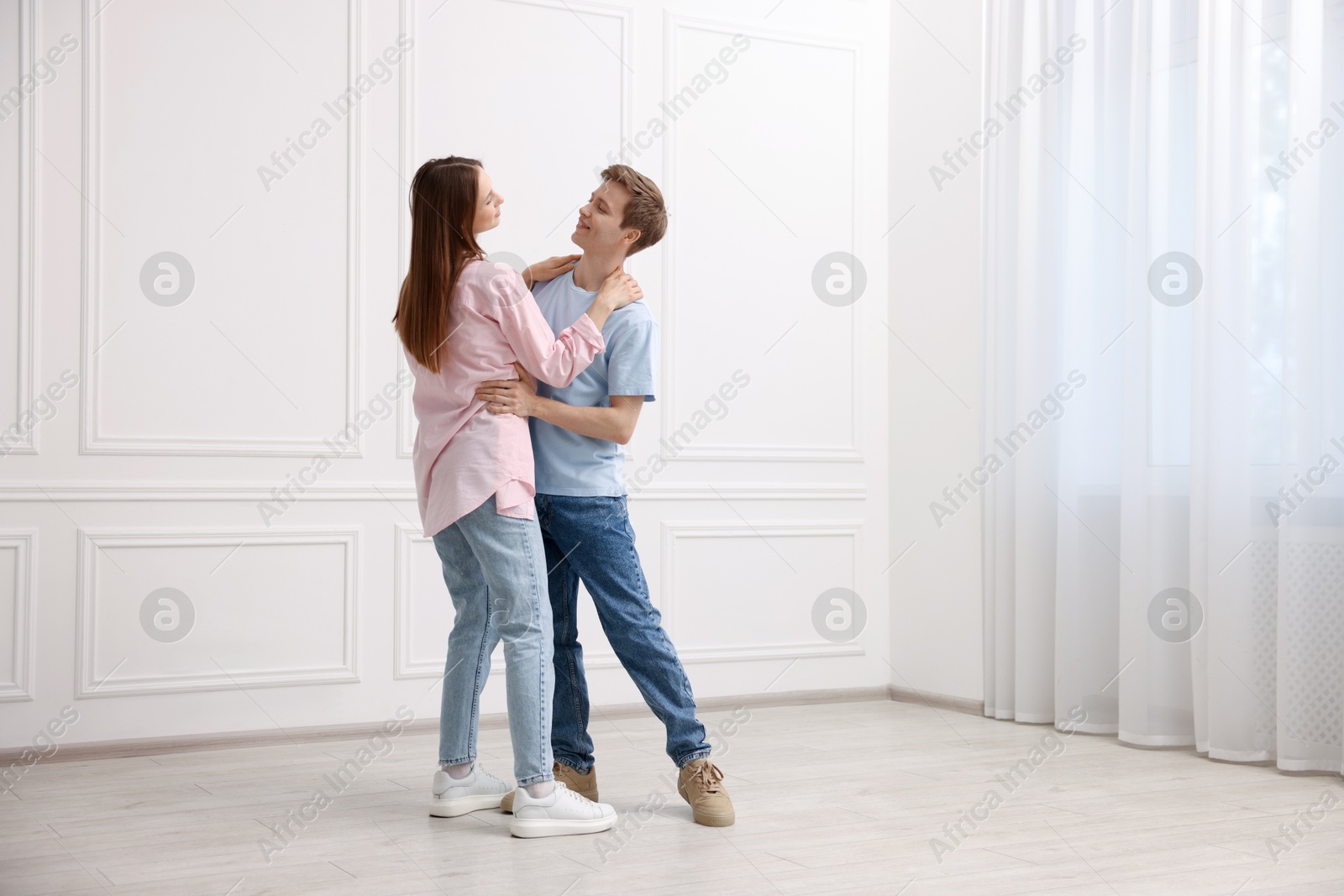 Happy couple dancing together near white wall at home Photo of Happy couple dancing together near white wall at home