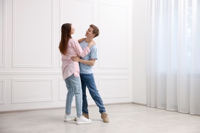 Photo of Happy couple dancing together near white wall at home