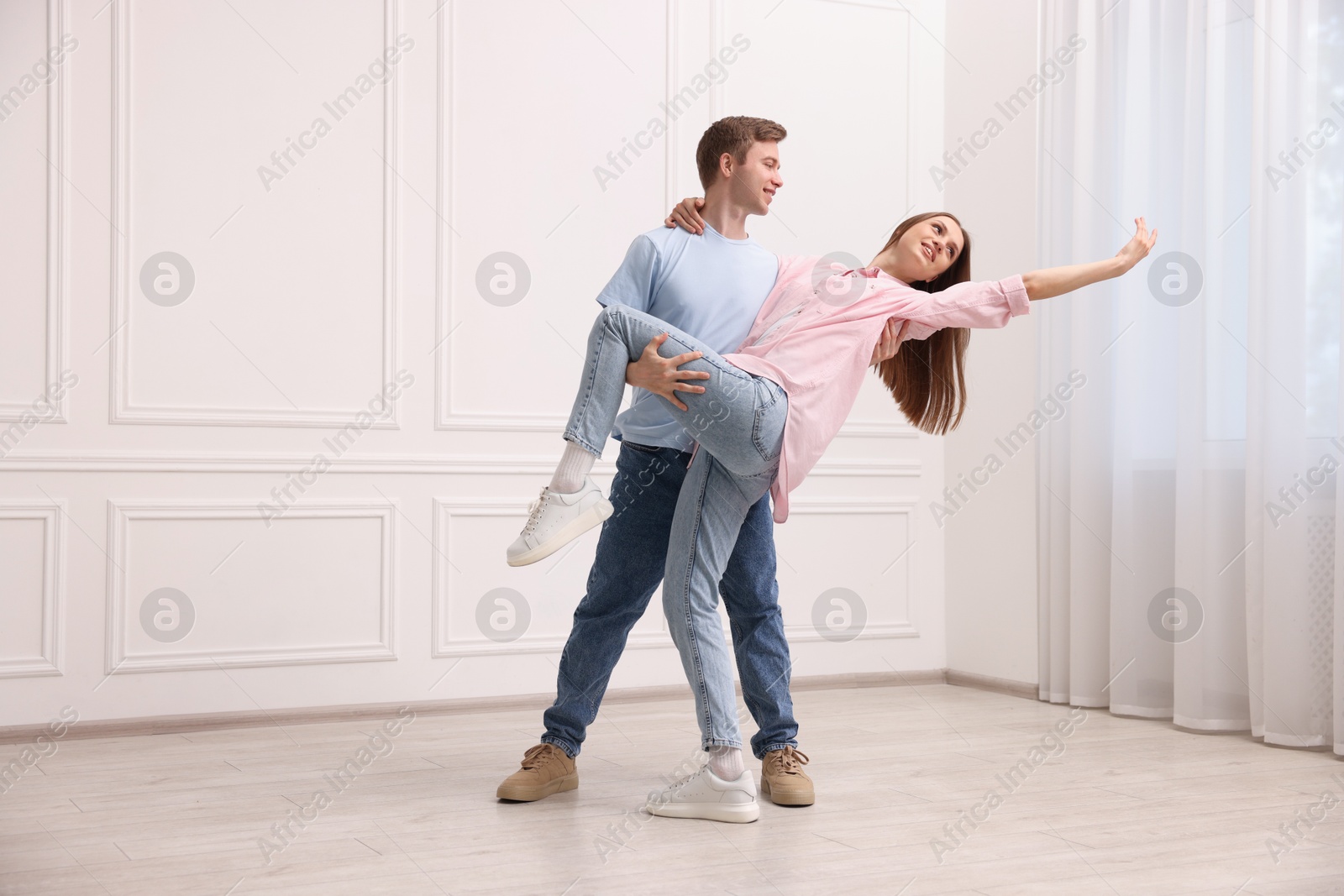 Happy couple dancing together near white wall at home Photo of Happy couple dancing together near white wall at home