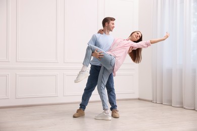Photo of Happy couple dancing together near white wall at home